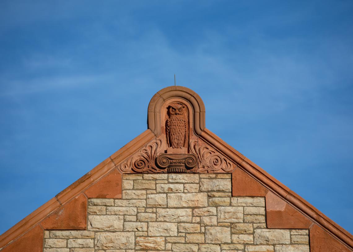 A sandstone owl perches in the peak of Spooner Hall