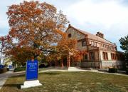 A tree shows its fall colors in front of Spooner Hall