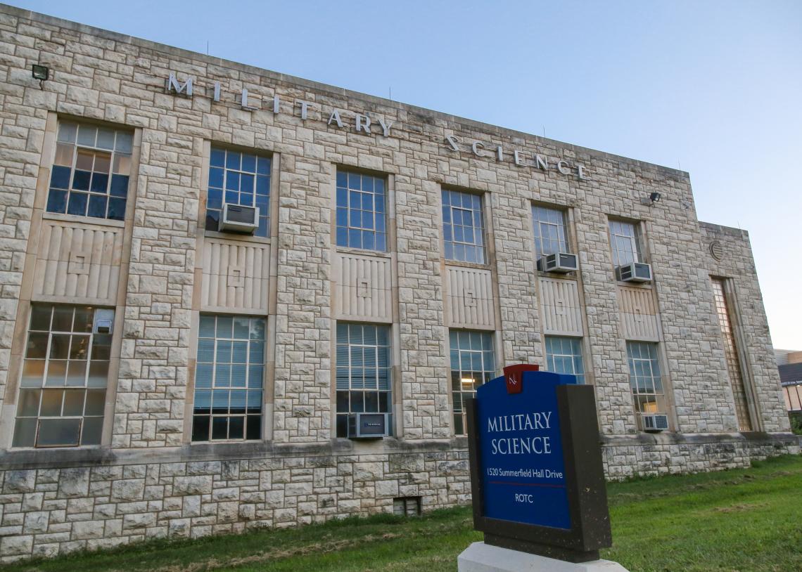 Limestone-faced building with blue sign out front that reads Military Science