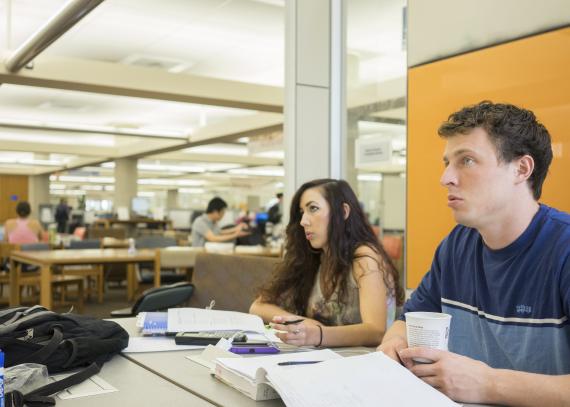 two students study together at a table in Anschutz Library