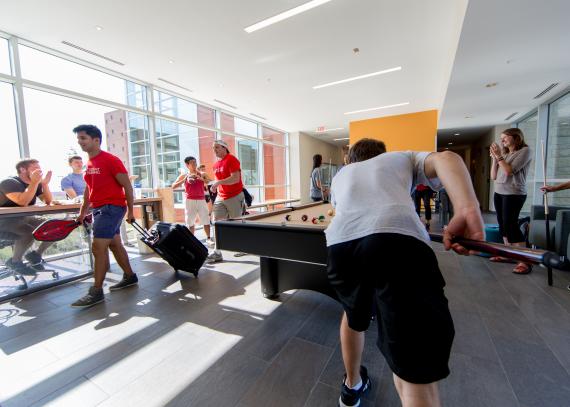 Students play billiards in a recreation area of Self Hall while several others relax around them