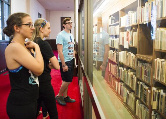 Students view a glass case filled with books from the collection