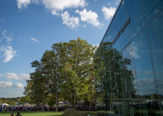 a tree, clouds, and a blue sky are reflected in the windows of the DeBruce Center