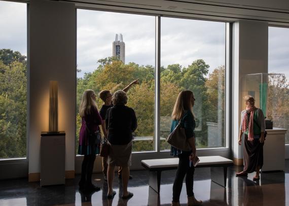 Several people tour the gallery with a view of the campanile in the background