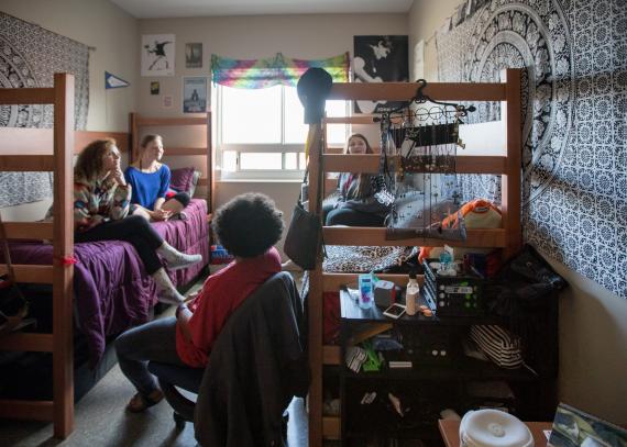 Four students gather in a student room in Oswald Hall