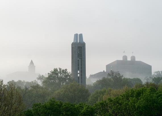 The tops of the Campanile, Fraser Hall, and Kansas Union seen through the fog on KU’s Lawrence campus