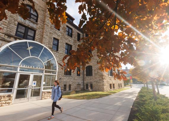 student walks past Bailey Hall on a fall day